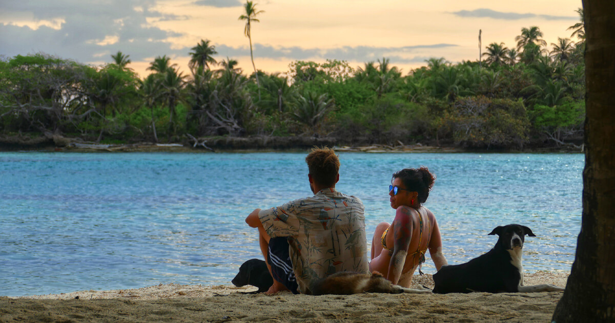 Founders of Go San Blas sitting on a beach in the San Blas Islands looking at the Caribbean Sea